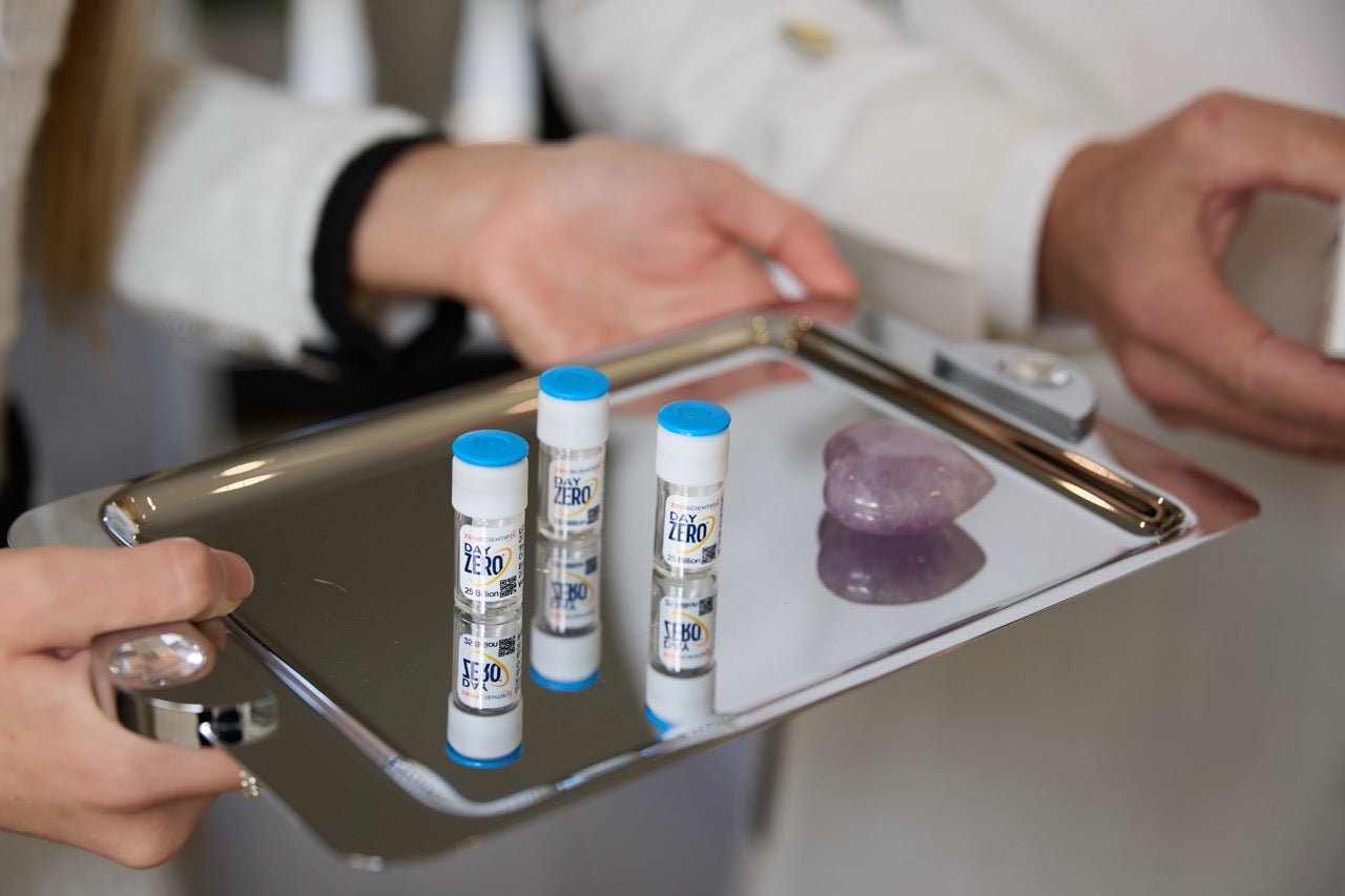 A person wearing black gloves opens a white box containing four small vials of MESOSOLUTION serum.