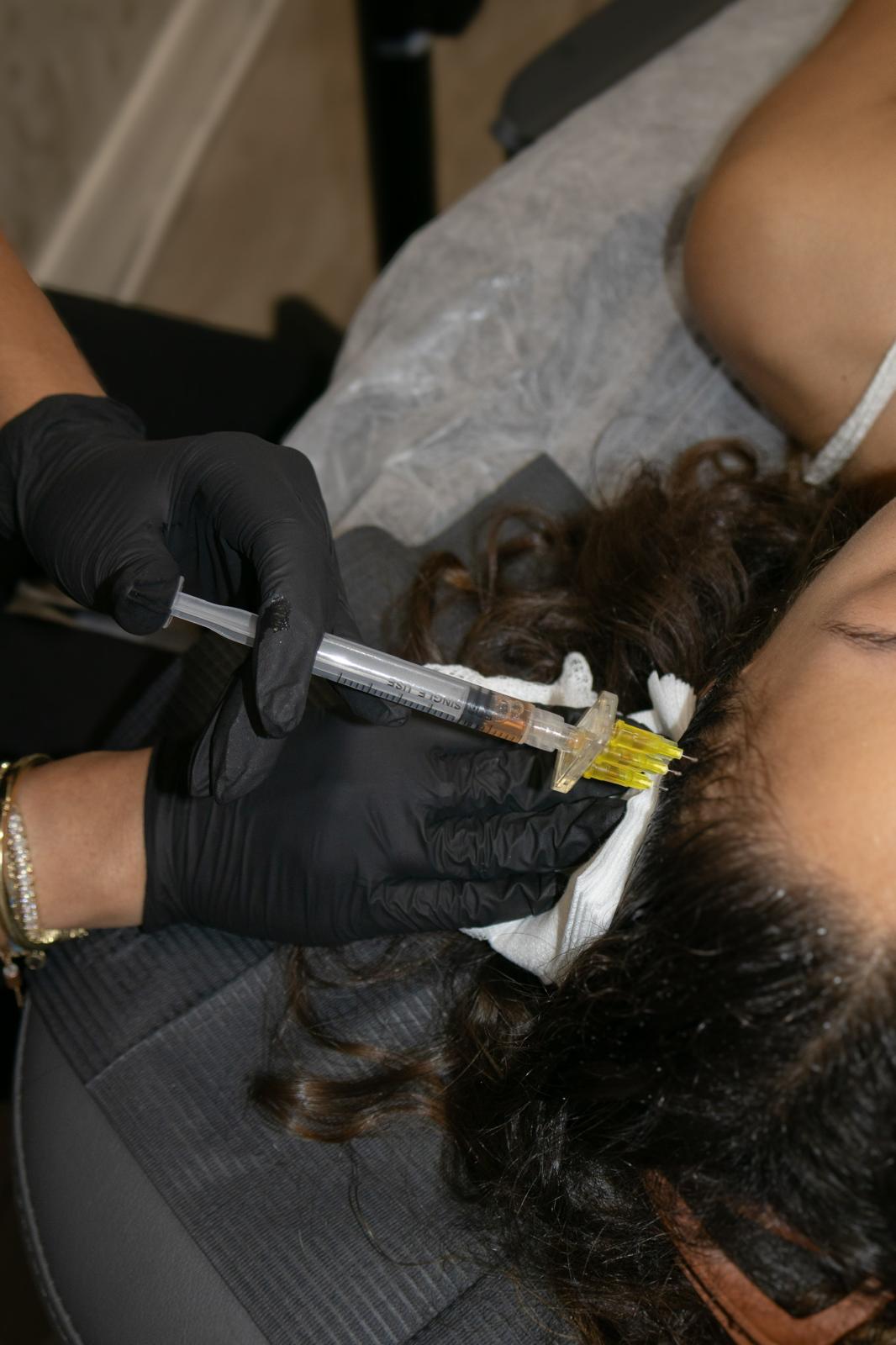 Gloved hands loading a syringe with yellowish liquid from a test tube containing separated layers of fluid.